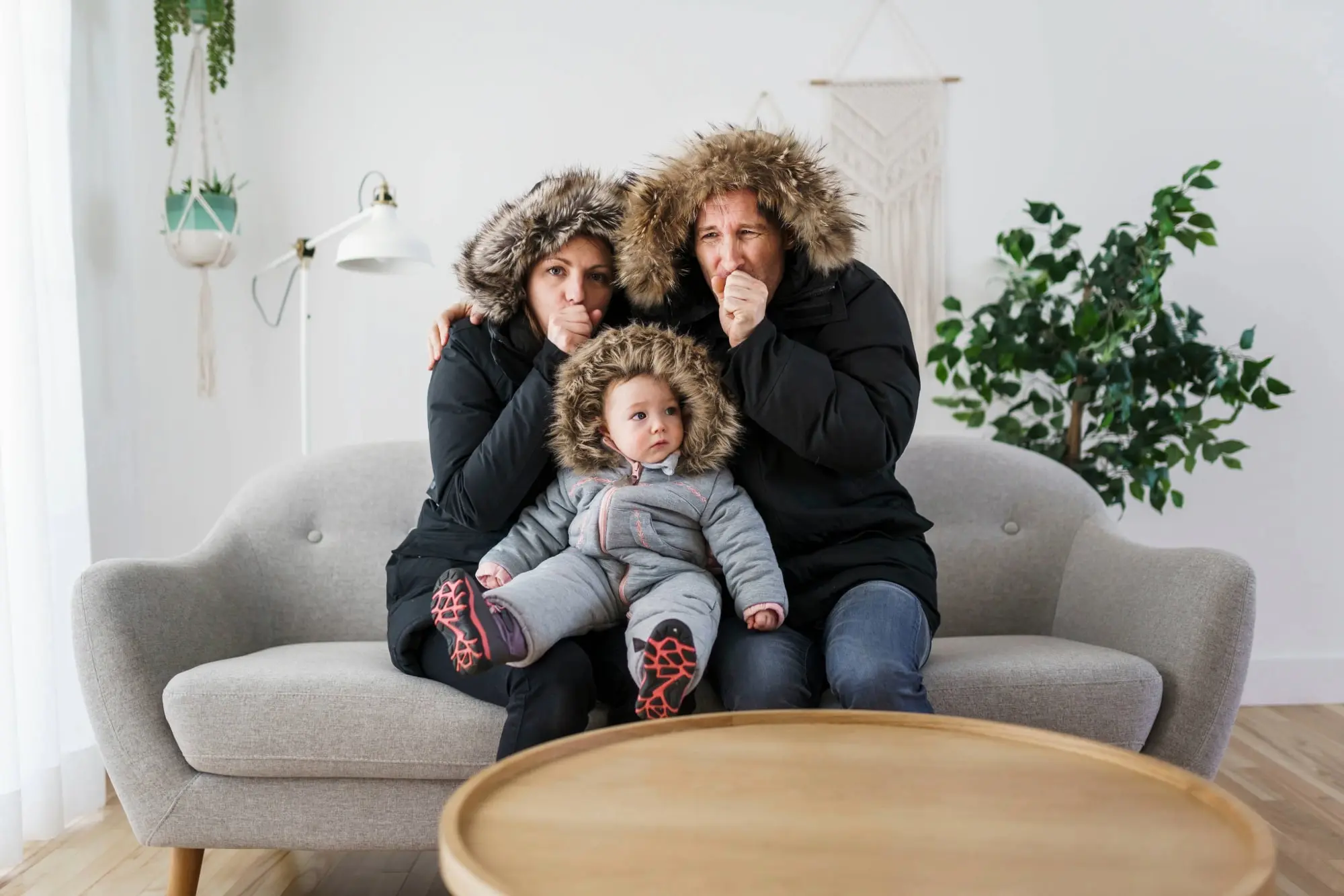 Young couple with Baby in parkas sitting in the cold